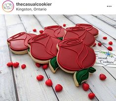 three decorated cookies sitting next to each other on top of a wooden table with red candies