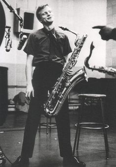 a man standing in front of a microphone holding a saxophone