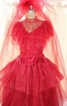 a red dress is displayed on a mannequin headdress with veils