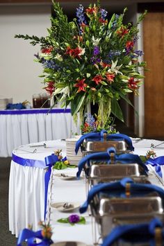 the table is set up with blue and white linens, silverware and flowers