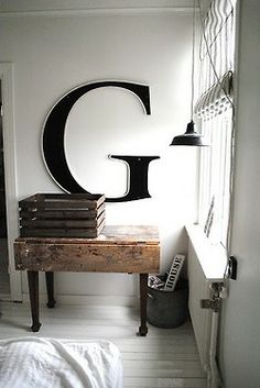 a room with a bed, table and lamp in it that has the letter g on it