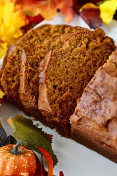 slices of pumpkin bread on a white plate with autumn leaves and oranges in the background