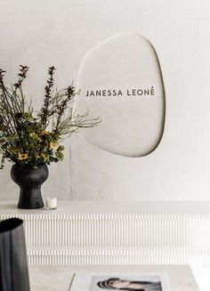 a vase filled with flowers sitting on top of a table next to a wall mounted sign