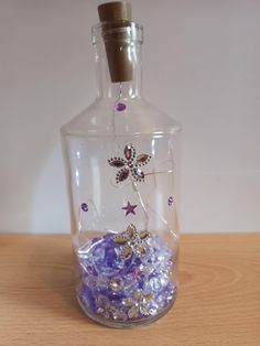 a glass bottle filled with lots of purple and white beads