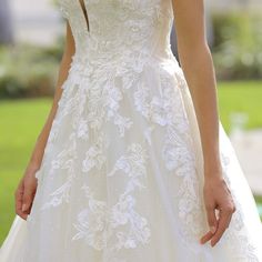 a woman in a white wedding dress holding her hand out to the side while standing outside