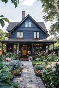 a blue house with lots of flowers in the front yard and walkway leading to it