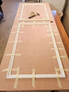 a wooden table with tape taped around the edges and tools on it, in front of a kitchen counter