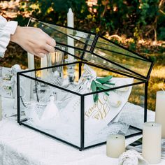 a glass box filled with wedding items on top of a table