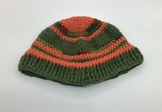 "Here is a crocheted beanie hat made with shades of green and orange acrylic yarn.  Measures 6 1/2\" by 11 1/2\".  Perfect gift for any special man in your life.  Machine wash warm; tumble dry; do not bleach; do not iron; dry cleanable." Green Casual Crochet Hat In Acrylic Yarn, Casual Green Crochet Hat, Green Brimmed Crochet Hat For Outdoor, Green Adjustable Crochet Beanie, Green Crochet Hat In Acrylic Yarn, Green Yarn Beanie Cap, Green Crochet Beanie Hat, One Size, Green Crochet Beanie Hat (one Size Fits Most), Hand Knitted Green Acrylic Beanie