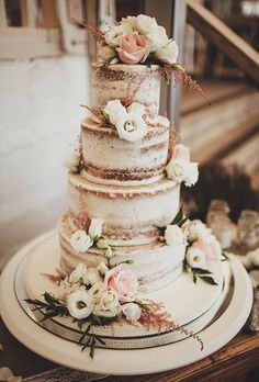 a three tiered wedding cake with flowers on the top and bottom is sitting on a table