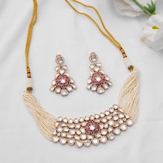 Embrace sophistication with this Kundan choker set, featuring delicate pearl lines and a charming pink floral center. Complete with exquisite dangler earrings, this set exudes elegance and is crafted with meticulous detail in mixed metal and 22kt gold plating. Finish: 22KT Gold Plating Material: Brass, Kundan,Pearls Color: Gold, White Size: Free Size, Adjustable Closure Type: Draw String Box Contains: 1 Necklace, 1 Pair Earrings Elegant Pink Jewelry Sets For Diwali, Elegant Pink Meenakari Choker, Elegant Pink Kundan Necklace For Festivals, Pink Elegant Kundan Necklace For Diwali, Elegant Pink Kundan Necklace For Diwali, Traditional Pink Kundan Necklace For Formal Occasions, Elegant Pink Meenakari Jewelry, Elegant Pink Pearl Necklace For Festivals, Elegant Pink Bridal Necklace For Festivals