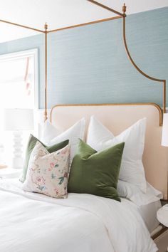 a bed with white sheets and pillows next to a table with two lamps on it