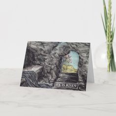 a card with an image of a cave and the words he is risen on it