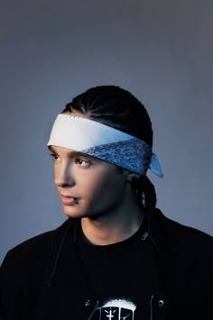 a young man wearing a headband and looking off to the side