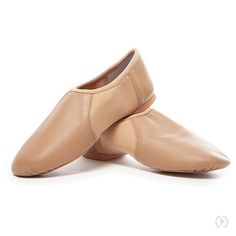 two tan ballet shoes sitting on top of each other in front of a white background