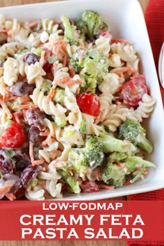 a pasta salad with tomatoes, broccoli and olives in a white bowl