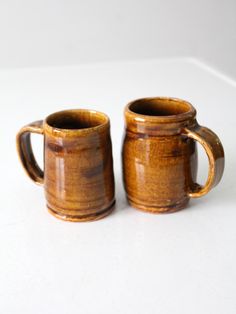 two brown mugs sitting next to each other on a table