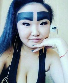 a woman with blue hair and black makeup has her face painted in the shape of a cross