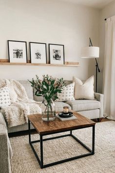 a living room with couches, tables and pictures on the wall above them in black frames