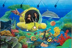 two men are sitting in a submarine surrounded by sea life