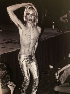 a shirtless man standing on stage with his hands behind his head