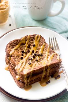 a piece of toast with peanut butter and chocolate chips on it next to a cup of coffee