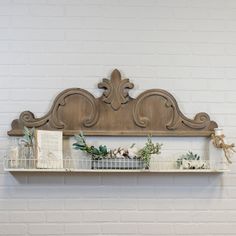 a shelf with flowers and books on it in front of a white brick wall,