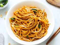 a white bowl filled with noodles next to chopsticks