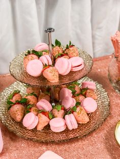 three tiered trays filled with pastries on top of a pink table cloth