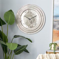 a clock is hanging on the wall next to a potted plant in a living room