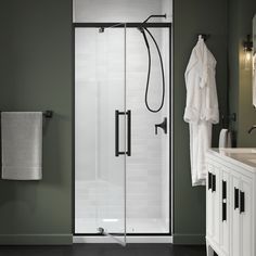 a bathroom with a walk in shower next to a white sink and black counter top