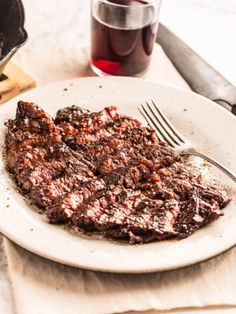 a white plate topped with meat next to a cup of tea and a spatula