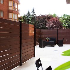 a table and chairs on a patio with wooden slatted fence in the background