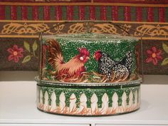 two tins sitting on top of a stove with chickens painted on the lids and sides