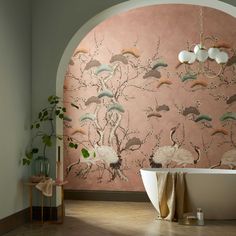 a bath tub sitting next to a pink wall with birds on it