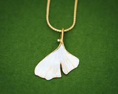 The ginkgo tree, a sacred tree of the East, is thought to be one of the oldest living trees, dating back to more than 200 million years. In Japanese decorative art, the ginkgo's distinctive fan-shaped leaf has been a symbol of longevity, profound endurance and unity of opposites. The Japanese Gingko Leaf series from the Shinji Classic Collection radiates timeless elegance. The Gingko Leaf series has been created with the gold and silver layering technique synonymous to the Shinji Classic collect White Leaf-shaped Jewelry Gift, Japanese Pendant, Necklace Japanese, Ginkgo Tree, Japan Gifts, Japanese Jewelry, Gingko Leaves, Sacred Tree, Head Chain