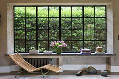 a room with a window, chair and books on the floor in front of it