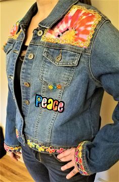 a woman wearing a jean jacket with the word peace on it