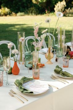 the table is set with glasses, plates and utensils for an outdoor dinner