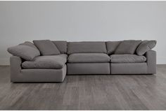 a large gray couch sitting on top of a wooden floor next to a white wall