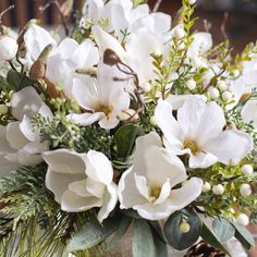 a vase filled with white flowers and greenery