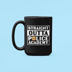 a black coffee mug with the words straight outa police academy on it and a cookie