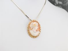 Versatile and lovely, this pin or pendant is beautifully crafted of yellow gold. The framework is a simple twist of polished metal, and the size of this piece lends itself well to wearing day to day as a signature cameo. The color of the shell is a rich, warm tan, and the carved cameo portion is creamy with hints of coral. This pendant does not come with the chain shown. Please feel free to contact us, we will help you find the perfect chain for your style and budget! Metal: 14K Yellow Gold Gem: Gold G, Cameo Ring, Cameo Brooch, Cameo Pendant, July Birthstone, To Day, Eternity Bands, Estate Jewelry, Vintage Gold