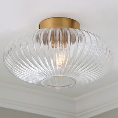 a glass light fixture hanging from the ceiling in a room with white walls and ceilings