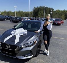 a woman standing next to a car with a bow on it