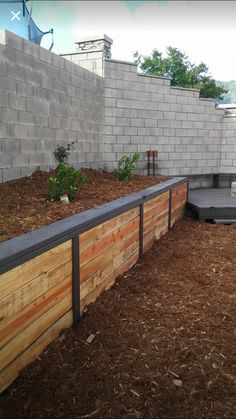 a wooden bench sitting in the middle of a yard next to a brick wall and fence