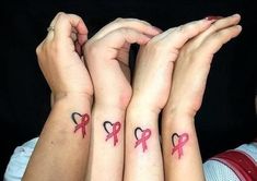 three people with matching tattoos holding hands together and wearing pink ribbon on their wrists