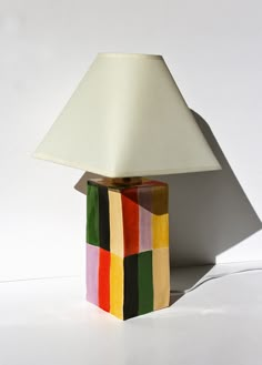 a colorful lamp with a white shade on it's base and a square design