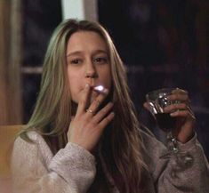 a woman sitting at a table with a glass of wine in front of her face