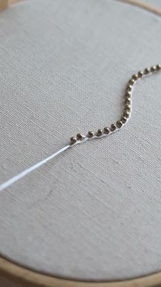 a close up of a cross stitching on a piece of fabric with a needle